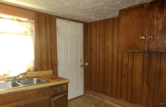 bathroom with wood walls, sink, and a textured ceiling