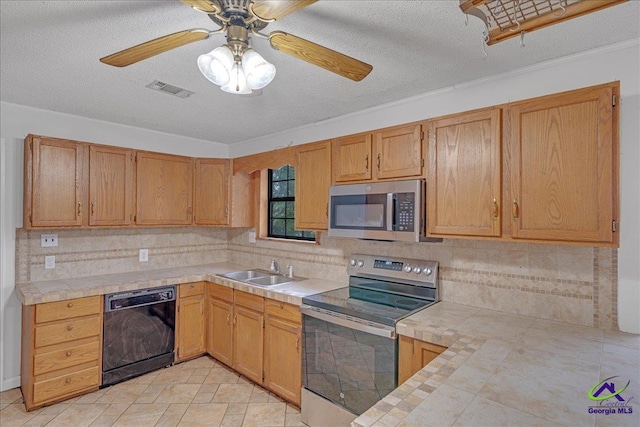 kitchen with tile countertops, appliances with stainless steel finishes, crown molding, sink, and ceiling fan