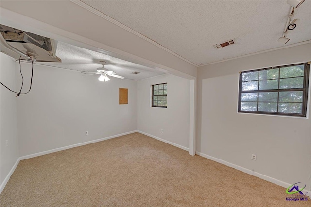 basement with a textured ceiling, light colored carpet, and ceiling fan