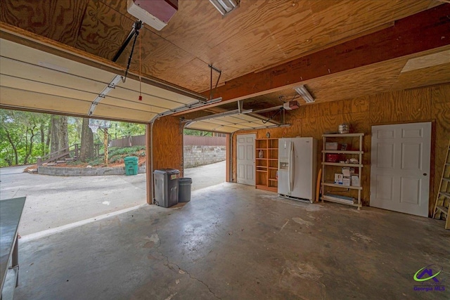 garage with a garage door opener, wooden walls, and white fridge with ice dispenser