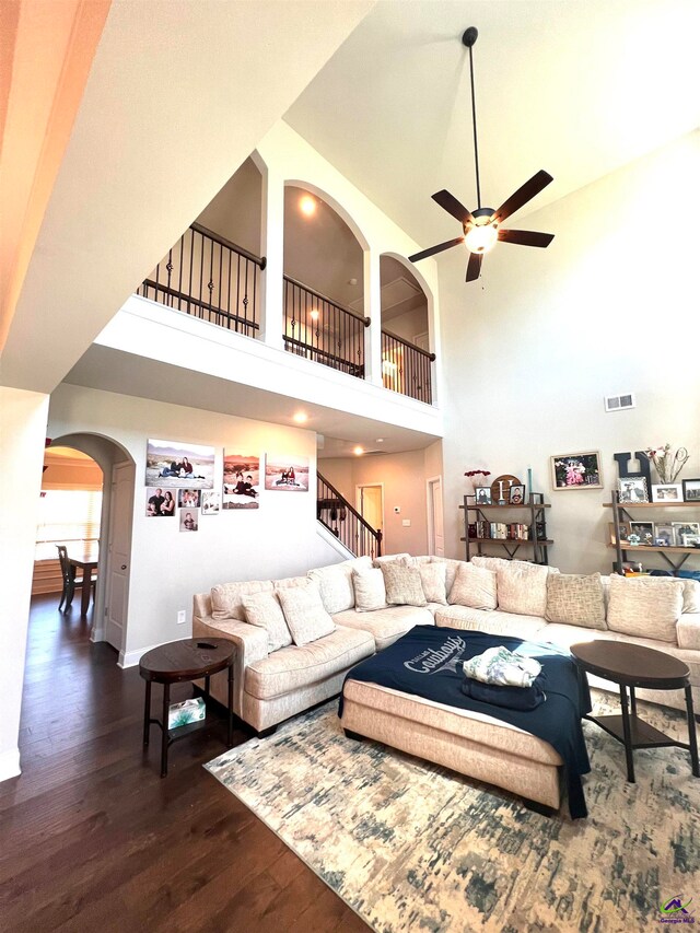 living room with a high ceiling, dark hardwood / wood-style flooring, and ceiling fan