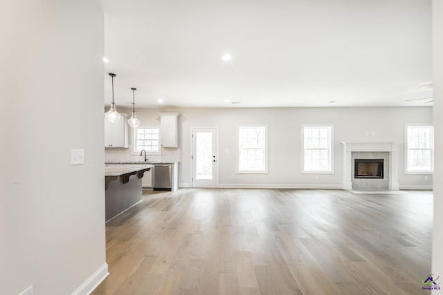 202 Bella Notte Cir, Warner Robins, GA 31088 - unfurnished living room featuring recessed lighting, a sink, light wood-style floors, a premium fireplace, and baseboards