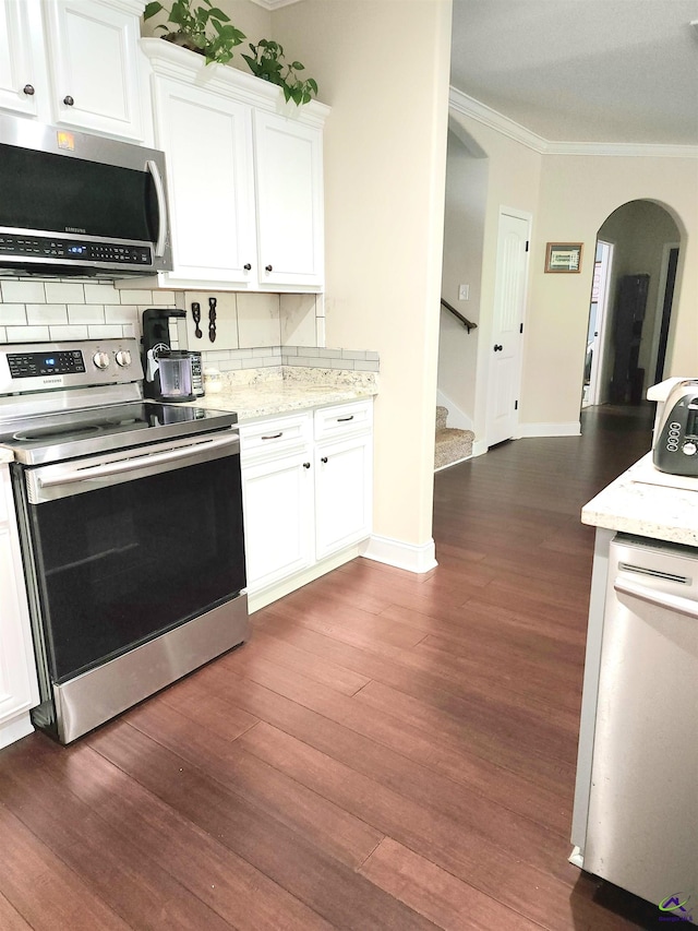 kitchen featuring white cabinetry, backsplash, appliances with stainless steel finishes, dark hardwood / wood-style flooring, and ornamental molding