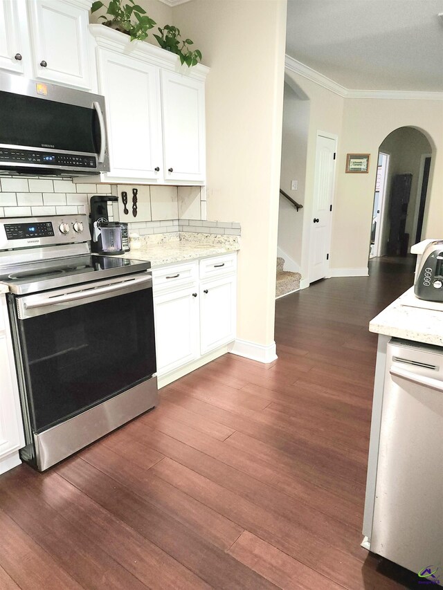 203 Lattice Bnd, Bonaire, GA 31005 - kitchen with appliances with stainless steel finishes, crown molding, decorative backsplash, dark wood-style flooring, and arched walkways