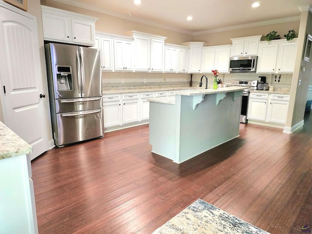 kitchen featuring white cabinets, light stone counters, appliances with stainless steel finishes, and dark wood-type flooring