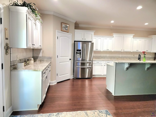 kitchen with light stone counters, dark hardwood / wood-style floors, stainless steel fridge with ice dispenser, and white cabinetry