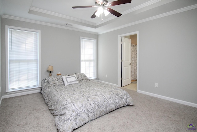 bedroom featuring ensuite bath, crown molding, a tray ceiling, and ceiling fan