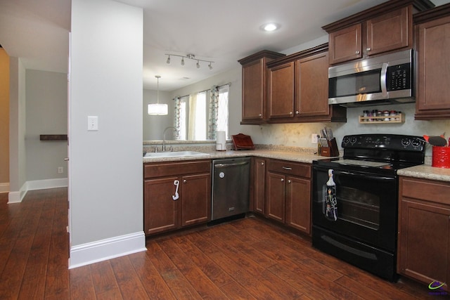 kitchen featuring appliances with stainless steel finishes, sink, pendant lighting, and dark hardwood / wood-style floors