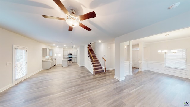 unfurnished living room with ceiling fan with notable chandelier and light hardwood / wood-style flooring