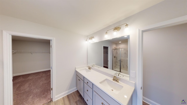 bathroom featuring hardwood / wood-style floors, a shower with door, and vanity