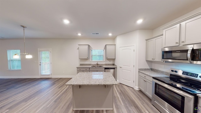 kitchen with appliances with stainless steel finishes, a center island, light wood-type flooring, and sink