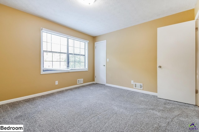 carpeted empty room featuring a textured ceiling