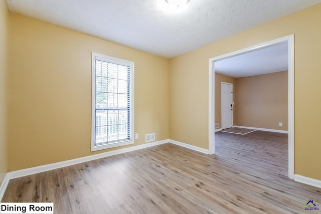 spare room with light wood-type flooring and a textured ceiling