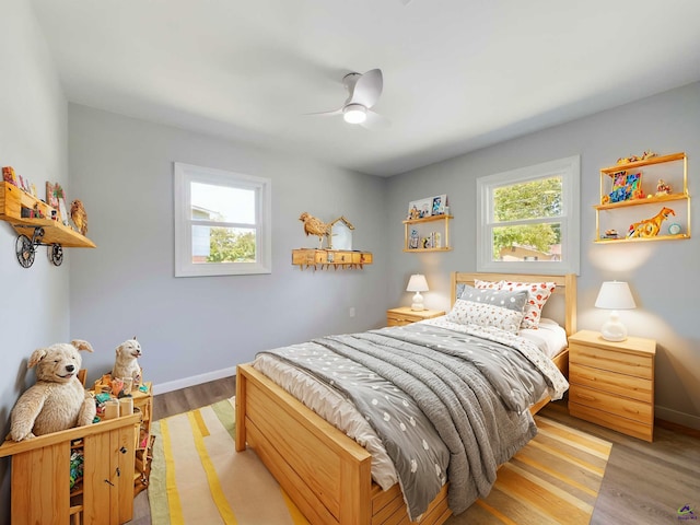 bedroom featuring ceiling fan, multiple windows, and light wood-type flooring