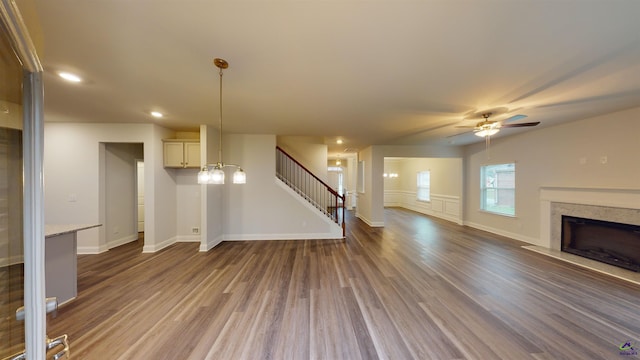 unfurnished living room with ceiling fan, dark hardwood / wood-style flooring, and a high end fireplace