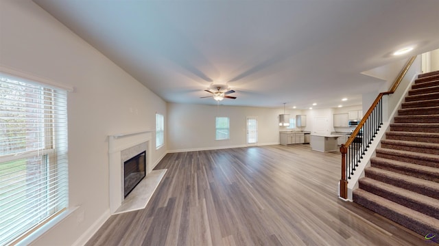 unfurnished living room with a high end fireplace, hardwood / wood-style floors, and ceiling fan