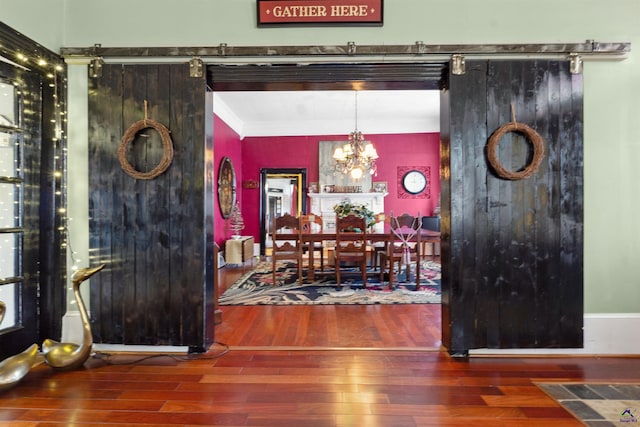 dining area featuring a chandelier, a barn door, crown molding, and dark hardwood / wood-style flooring