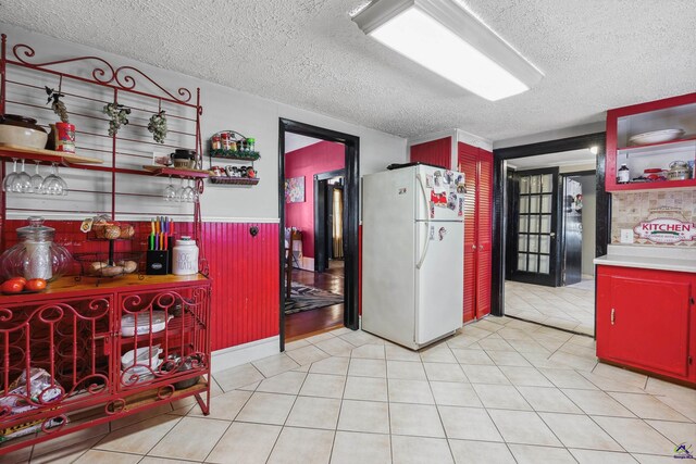 kitchen with light tile patterned floors, a textured ceiling, and white fridge