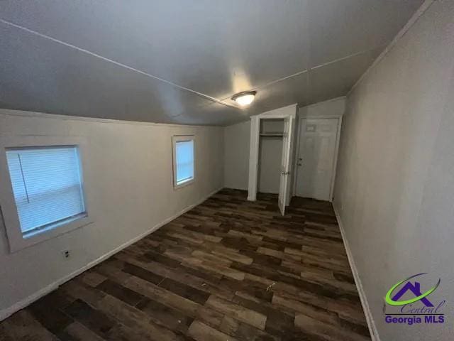 additional living space featuring lofted ceiling and dark wood-type flooring