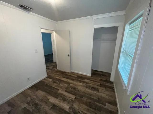 unfurnished bedroom featuring dark hardwood / wood-style floors and a closet