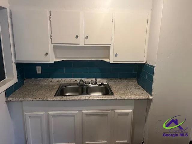 kitchen featuring decorative backsplash, white cabinetry, and sink