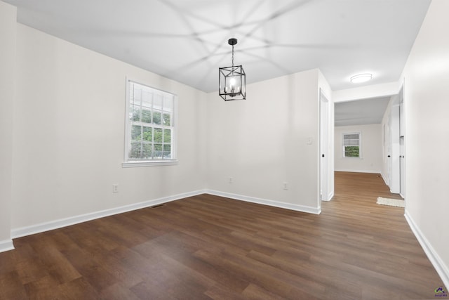 spare room featuring a chandelier and dark hardwood / wood-style flooring