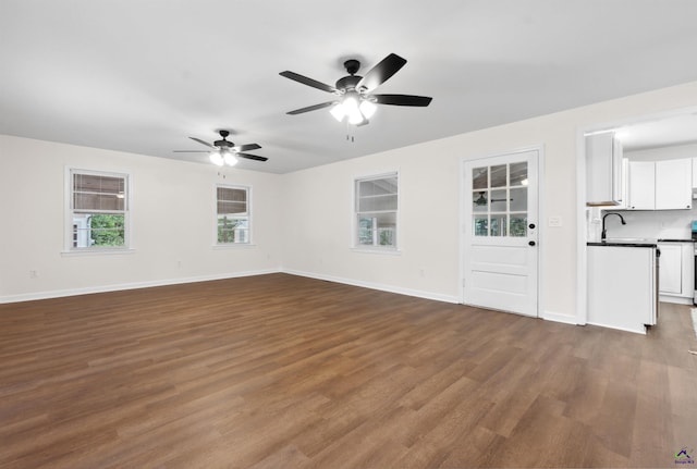 unfurnished living room with ceiling fan, sink, dark hardwood / wood-style flooring, and a healthy amount of sunlight