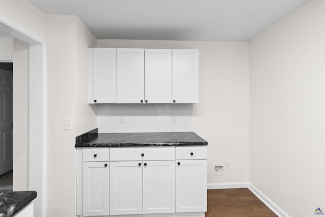 kitchen with white cabinets, dark stone counters, dark hardwood / wood-style flooring, and tasteful backsplash