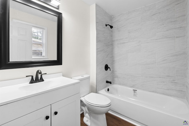 full bathroom featuring tiled shower / bath, vanity, and toilet