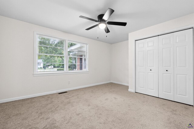 unfurnished bedroom with ceiling fan, a closet, and light carpet