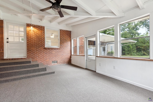 interior space featuring beamed ceiling, ceiling fan, and brick wall