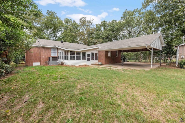 back of house with a yard, a carport, and central AC unit