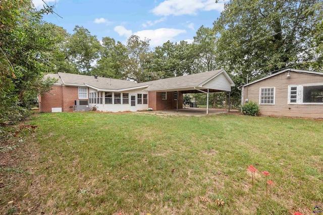 rear view of house featuring a lawn, a carport, and a patio