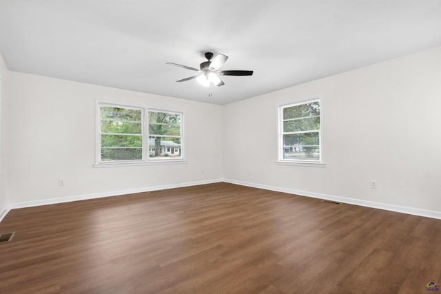 empty room with a wealth of natural light, ceiling fan, and dark hardwood / wood-style flooring