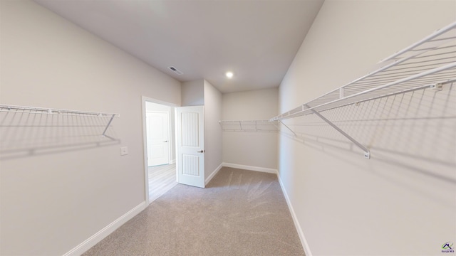 walk in closet with light carpet