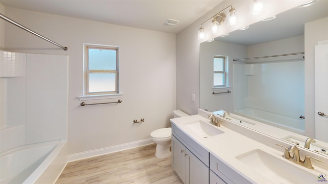 full bathroom with wood-type flooring, shower / washtub combination, a healthy amount of sunlight, and toilet