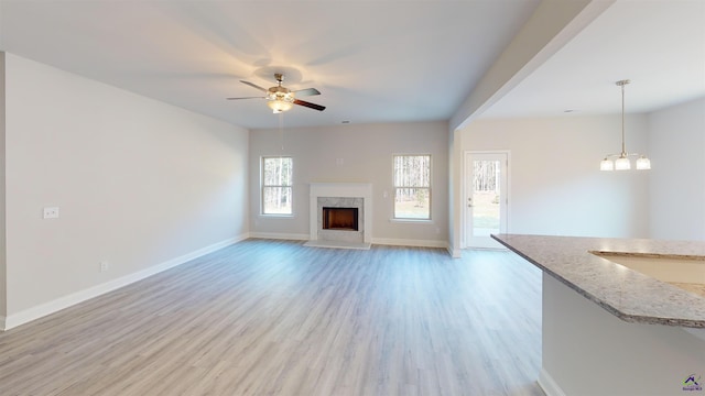 unfurnished living room featuring ceiling fan, a premium fireplace, and light hardwood / wood-style flooring