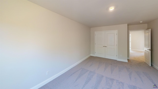 unfurnished bedroom with light carpet and a closet