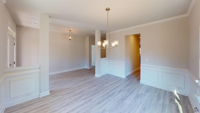 empty room with light hardwood / wood-style flooring, an inviting chandelier, and ornamental molding