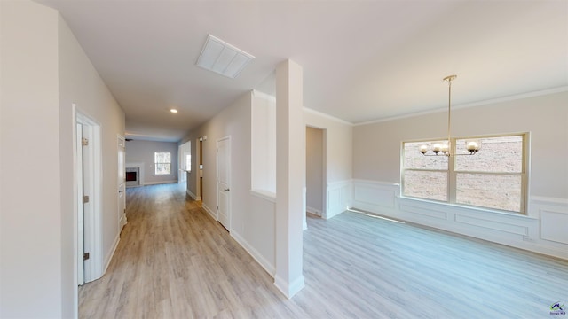 hall featuring light hardwood / wood-style flooring, an inviting chandelier, and crown molding