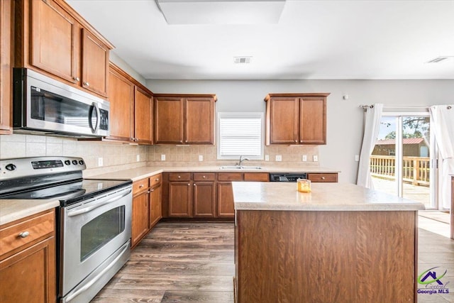 kitchen featuring sink, stainless steel appliances, dark hardwood / wood-style flooring, and a center island