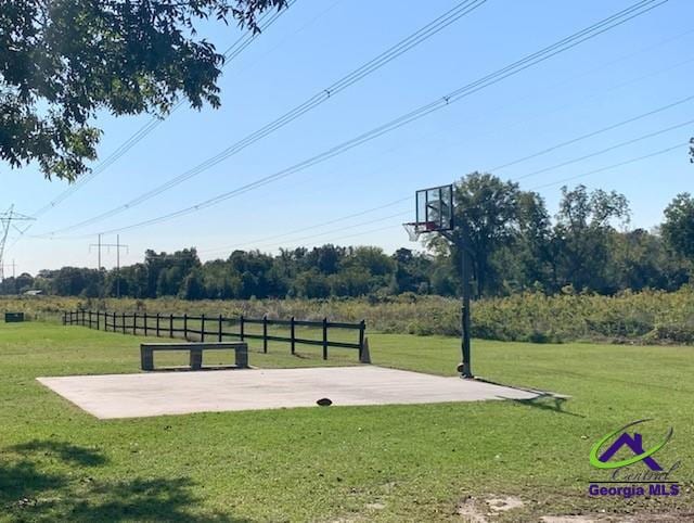 view of sport court with a rural view and a lawn