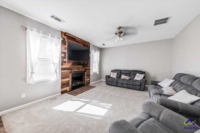 living room with ceiling fan, plenty of natural light, carpet, and a large fireplace