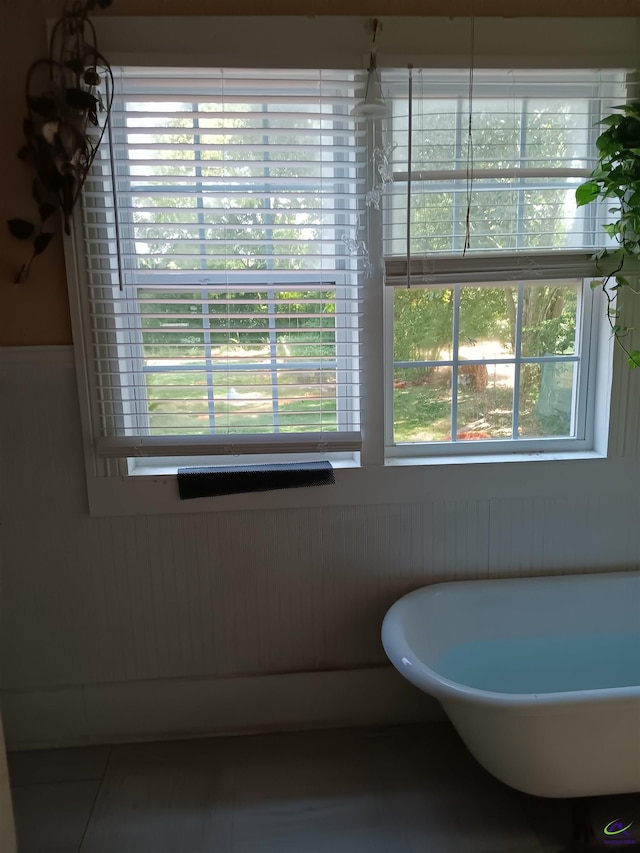 bathroom featuring a washtub, tile patterned floors, and wood walls