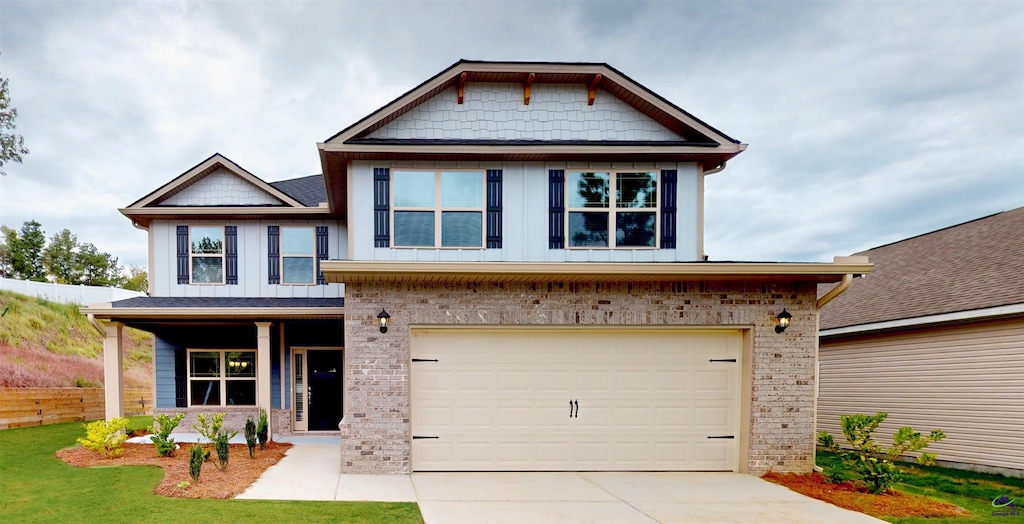 craftsman-style home with driveway, board and batten siding, a front yard, brick siding, and a garage