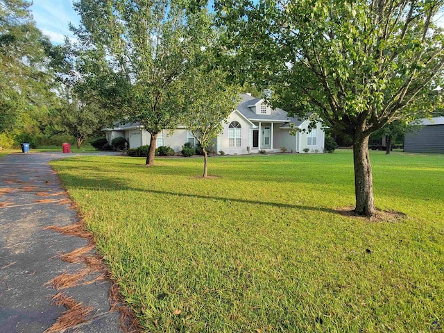 obstructed view of property featuring an attached garage, aphalt driveway, and a front lawn