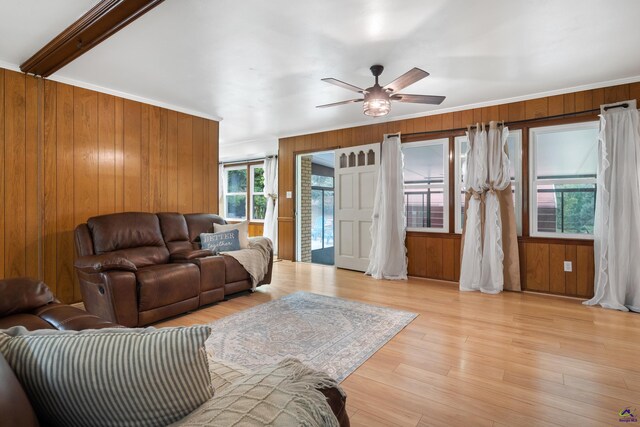 living room with beamed ceiling, wooden walls, ceiling fan, and light hardwood / wood-style flooring