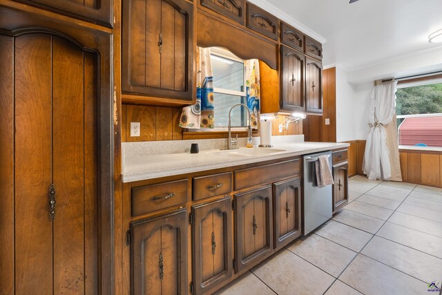 kitchen with stainless steel dishwasher, crown molding, light tile patterned flooring, and sink