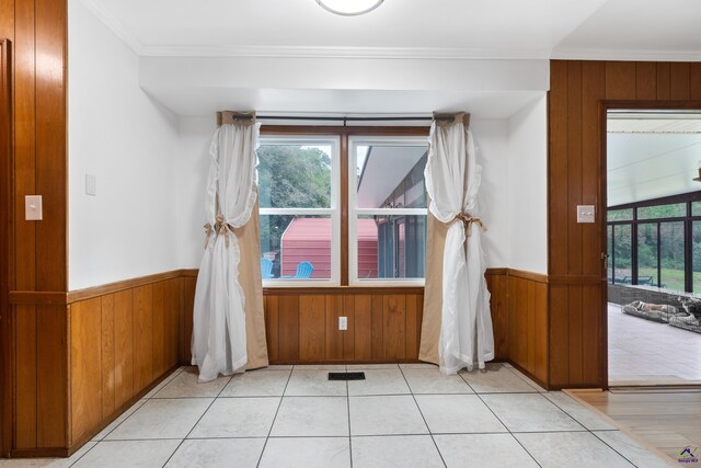 spare room featuring light tile patterned flooring, wooden walls, and crown molding