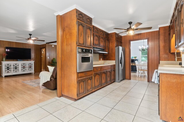 kitchen with appliances with stainless steel finishes, wood walls, and crown molding